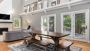 A modern living room with a large dining table, gray sofa, and a fireplace. - Bright & Modern 5 BR Wintergreen Home; Minutes from Hiking, Skiing, and Wineries (Wintergreen)