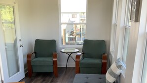 A cozy room with a dining table, two green armchairs, a grey ottoman, and a small round table with books. - Rusty Hook located in Cypress Cove Marina   (Venice)