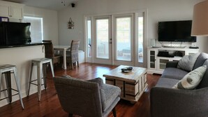 A living room with a sofa, a coffee table, and a TV. There are two chairs, a small table, and a cabinet with a TV. - Rusty Hook located in Cypress Cove Marina   (Venice)