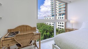 A hotel room with a large window, a bed, a desk with a chair, and a nightstand. - Coconut Grove Retreat, bayviews, 1 park incl, wkspace, Smart TV, Pool/hottub" (Coconut Grove)