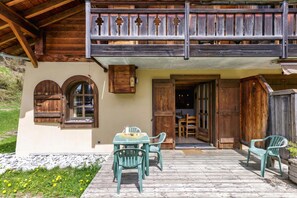 A wooden balcony with a railing, a table with chairs, and a door leading to an interior space. - Chalets d'Henri 67, Argentière (Chamonix), France (Argentière (Chamonix))