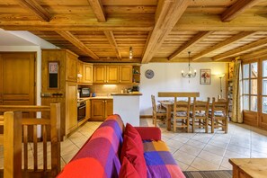A cozy wooden interior with a kitchen, dining area, and a sofa with colorful cushions. - Chalets d'Henri 67 Apartment w/ Terrace & Mont Blanc Views, Argentière (Chamonix), France (Argentière (Chamonix))