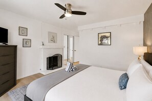Un dormitorio con cama, chimenea, ventilador de techo y televisor.