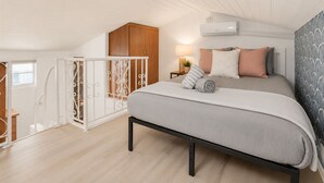 A bedroom with a bed, a nightstand, an air conditioning unit, and a window. - Beach House 85-Just One House from the Sand! (Ventura)