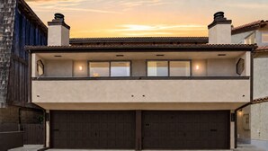 A two-story residential building with a garage, a balcony, and a sunset view.