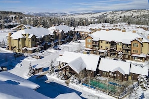 A resort with multiple buildings, a swimming pool, and a snowy landscape.