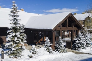 A lodge with a snow-covered roof, wooden exterior, and snow-laden trees.