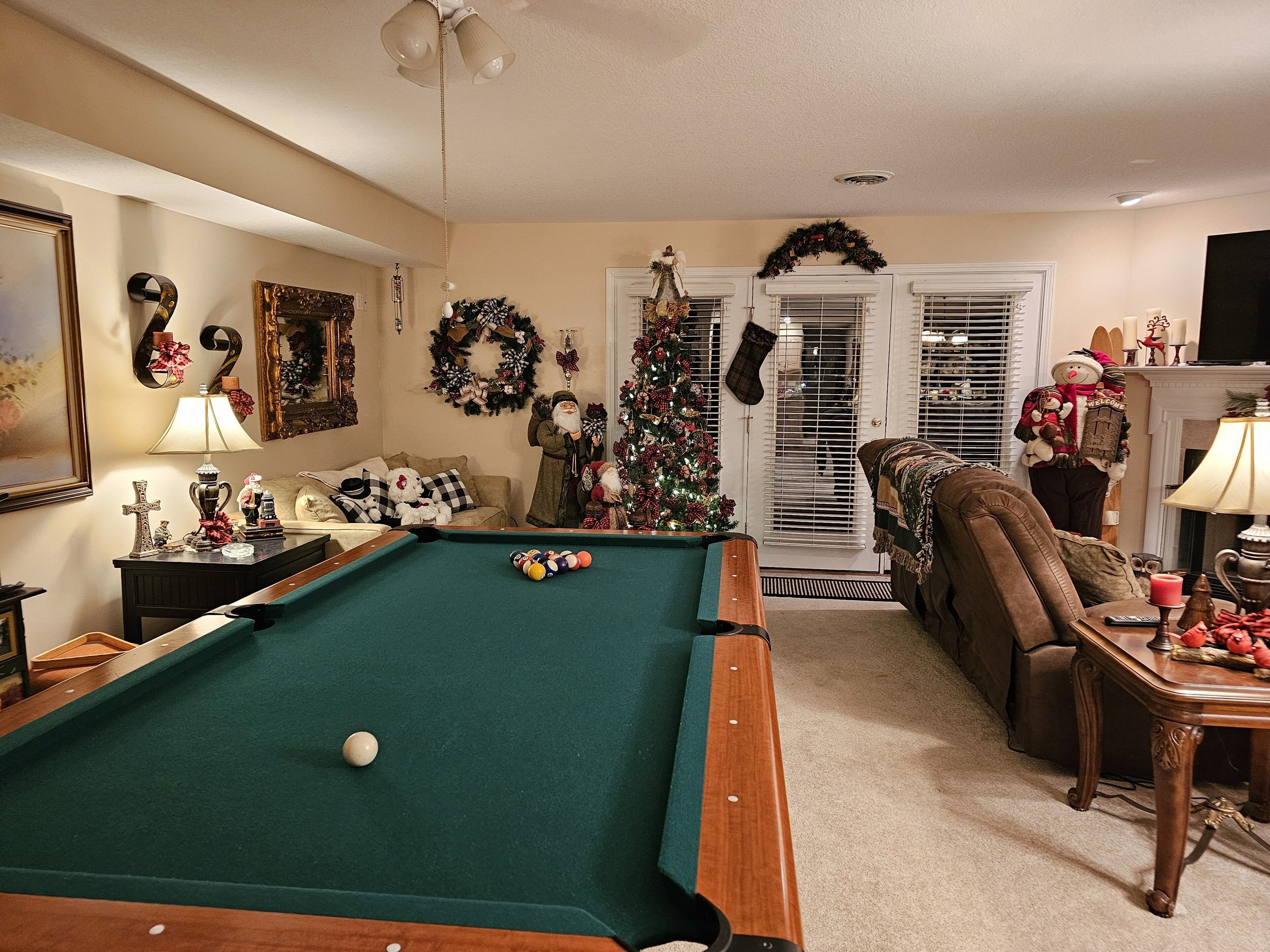 A cozy living room with a pool table, a Christmas tree, and festive decorations.