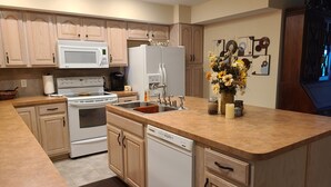 A modern kitchen with wooden cabinets, a white stove, a microwave, a refrigerator, and a dishwasher. - Relaxing Executive Condo at Big Bear Resort - Kentucky Lake views (Benton)