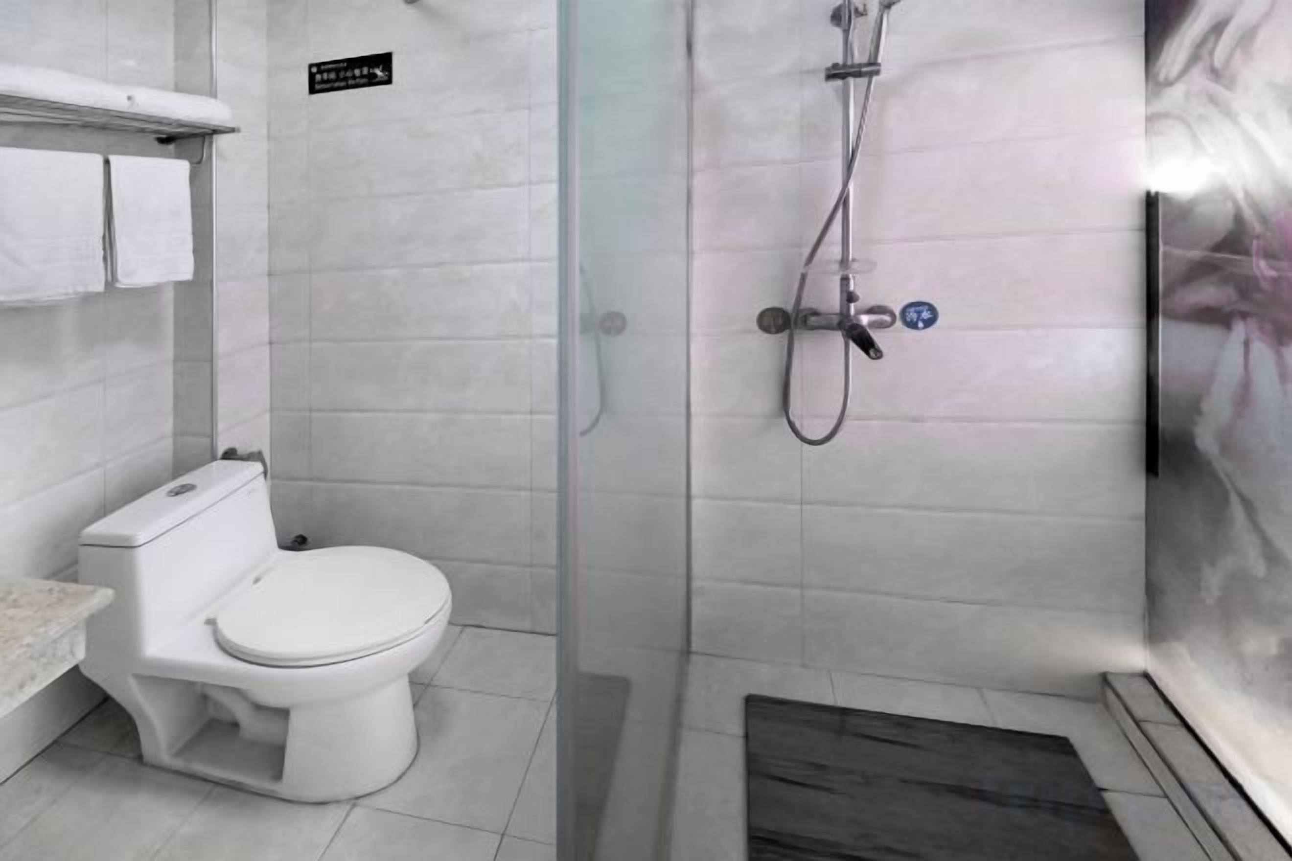 A bathroom with a toilet, a shower enclosure, and a tiled floor.