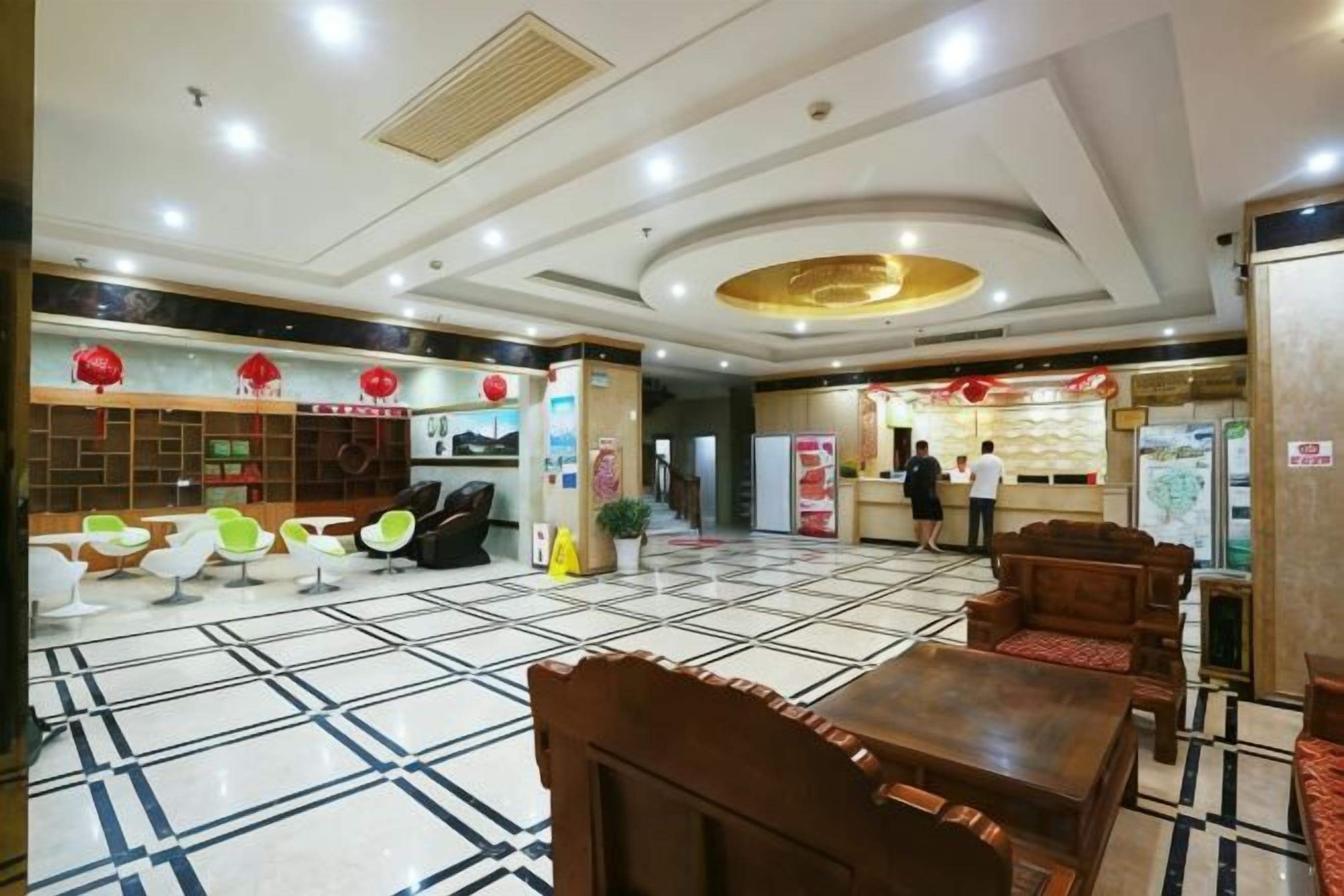 A hotel lobby with a reception desk, seating area, and a tiled floor.
