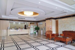 Un hall d’h ôtel comprenant un comptoir d’accueil, un espace salon et un grand lustre.