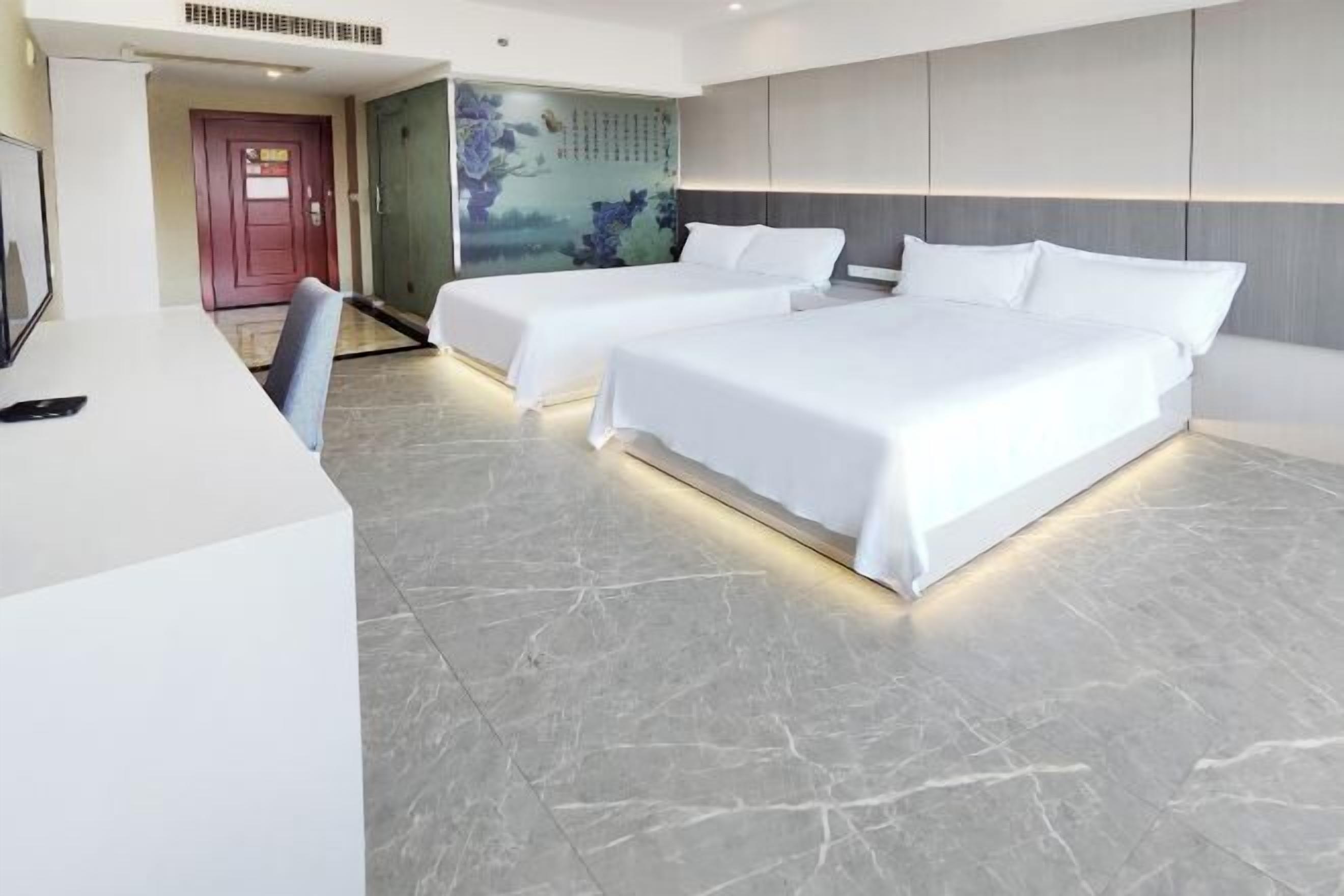 Ein Hotelzimmer mit zwei Betten, einem Schreibtisch und einem Wandgemälde.