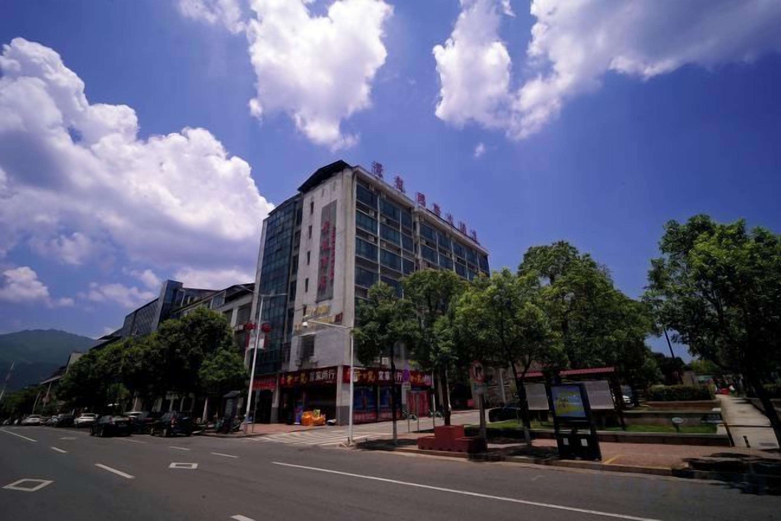 A multi-story building with a modern architectural design, located on a street with a clear sky and clouds.