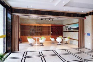 A lobby with a modern design, featuring a seating area with white chairs and a wooden wall with artwork. - Jinglong International Hotel (Yanling)