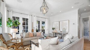 A spacious living room with a sofa, chairs, a coffee table, and a chandelier. - Palm Filled Paradise at Petite Palm / Golf Cart / 3 Min Walk to Beach / Community Pool / 4 Bikes (Santa Rosa Beach)