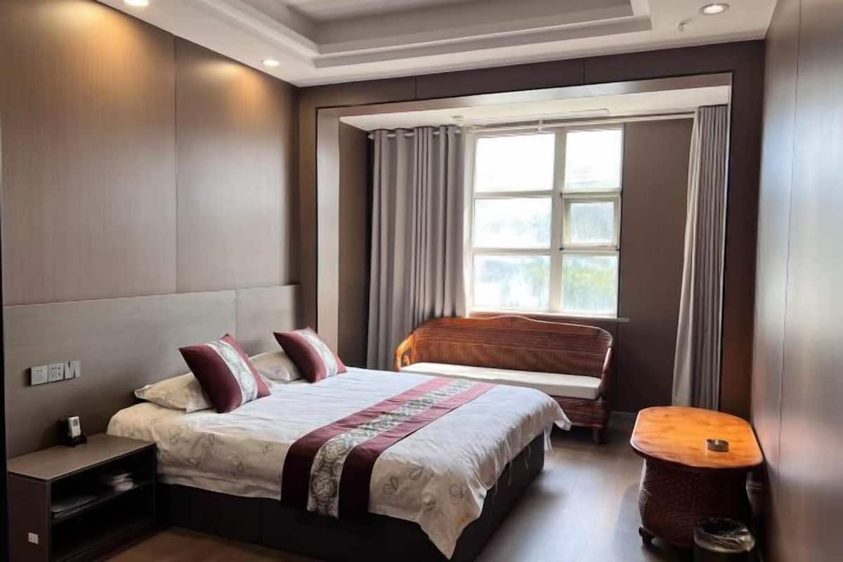 Ein Hotelzimmer mit Bett, Nachttisch und einem fenster mit Vorhängen.
