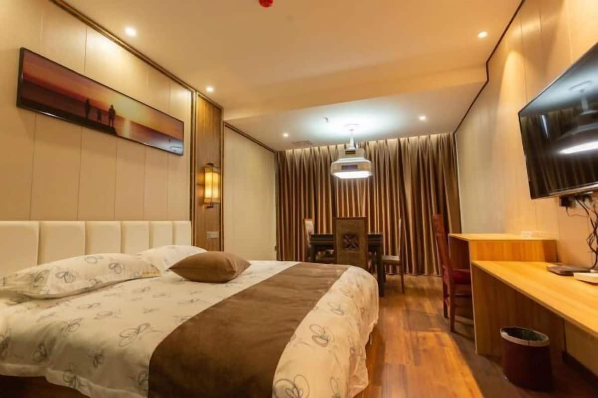 Ein Hotelzimmer mit Bett, Schreibtisch, Fernseher und einem Gemälde an der Wand.