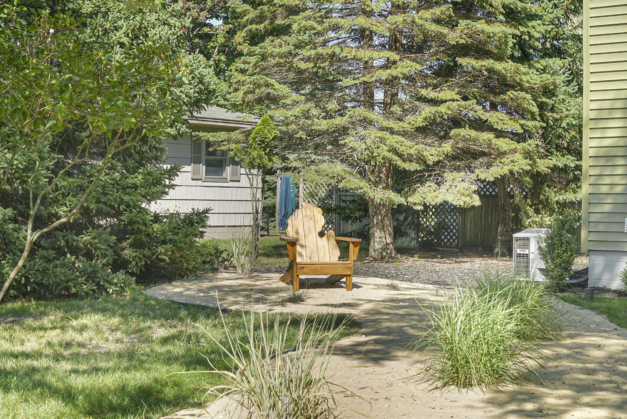 A wooden chair in a garden area with a house in the background.