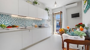 Une cuisine moderne avec des meubles blancs, un pare-feu en carreaux et un coin repas avec une table dressée pour deux personnes.