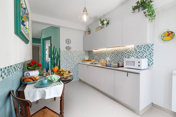A kitchen with white cabinets, a tiled backsplash, and a dining area with a table set for breakfast.