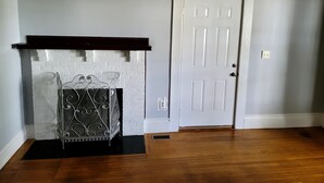 Una habitación con chimenea, puerta y suelo de madera.