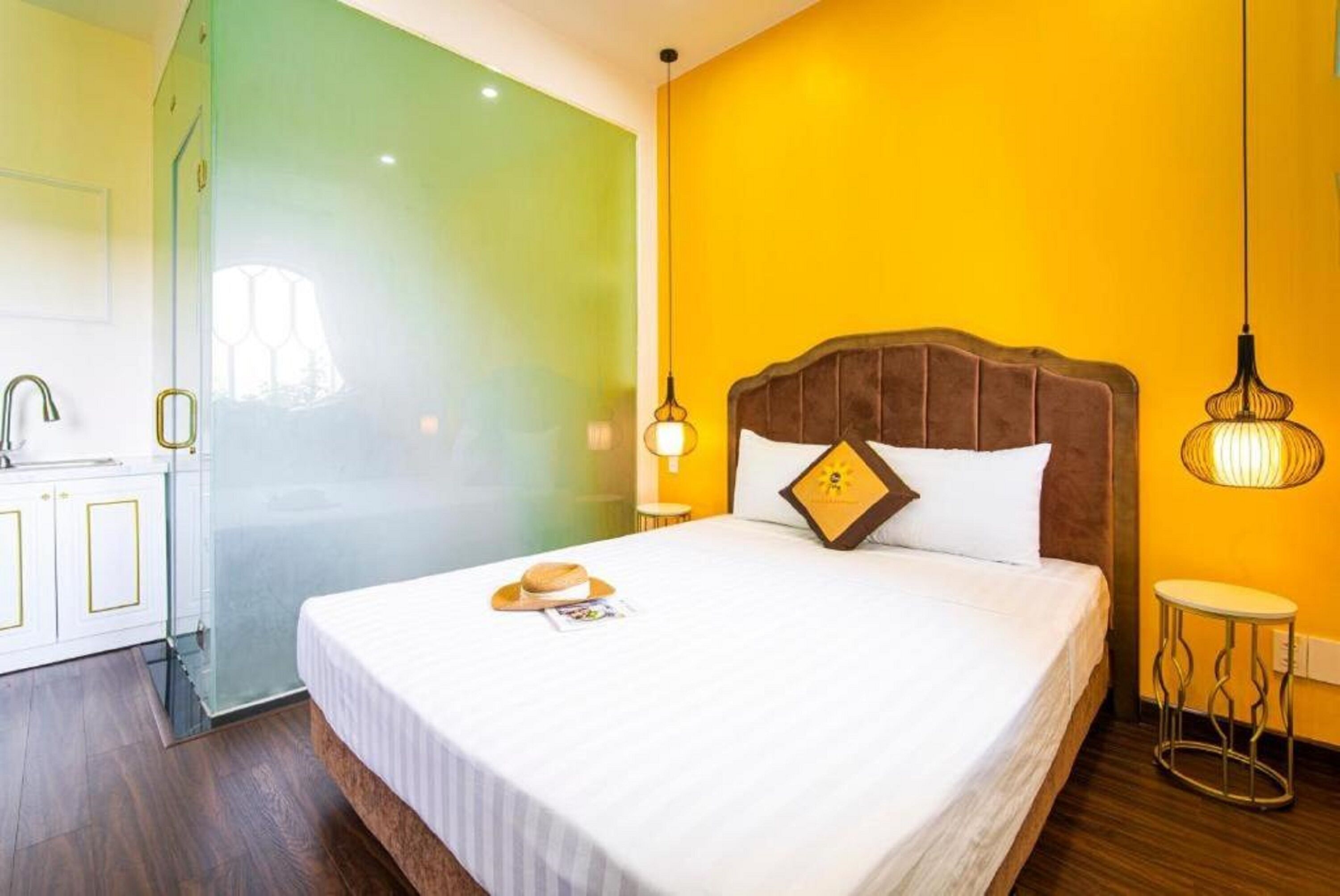Une chambre d’hôtel avec un lit, une table de chevet, une lampe et une vue sur un mur végétal et une porte.