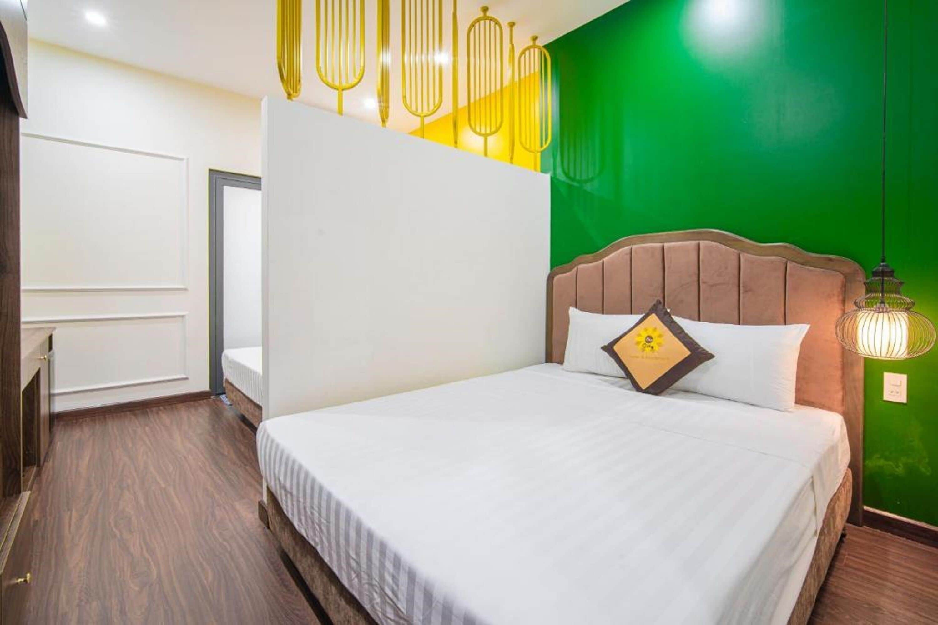 Une chambre d’hôtel avec un grand lit, une armoire en bois et un mur d’accent vert.