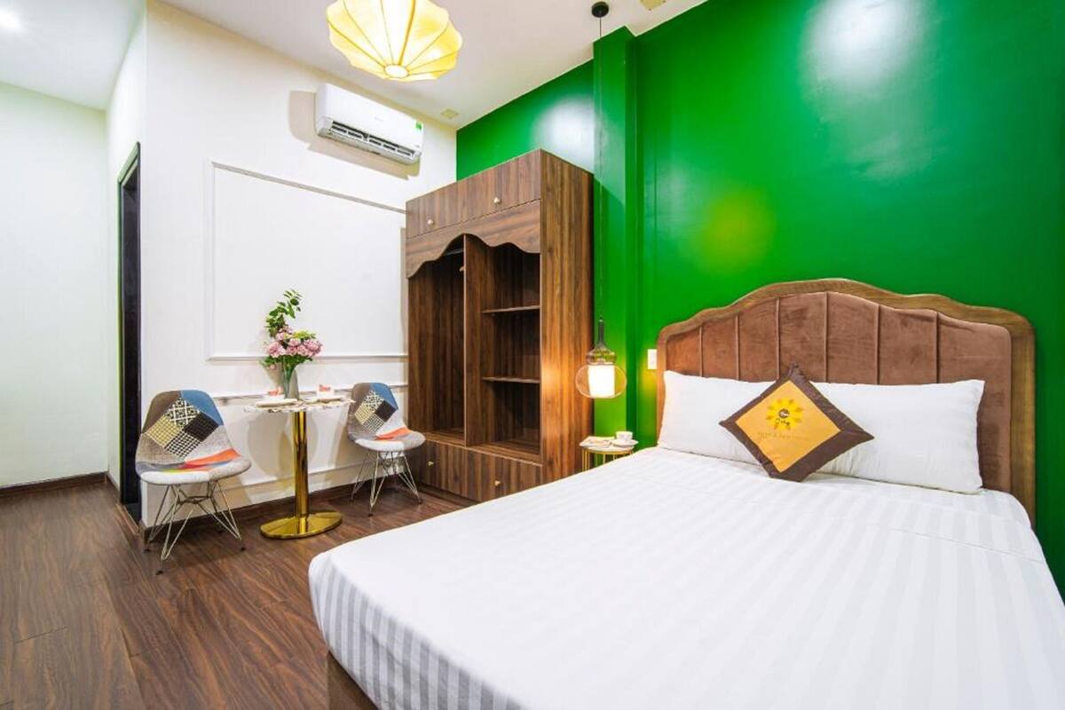 Una habitación de hotel con una cama grande, un armario de madera, un escritorio con dos sillas y una pared de acento verde.