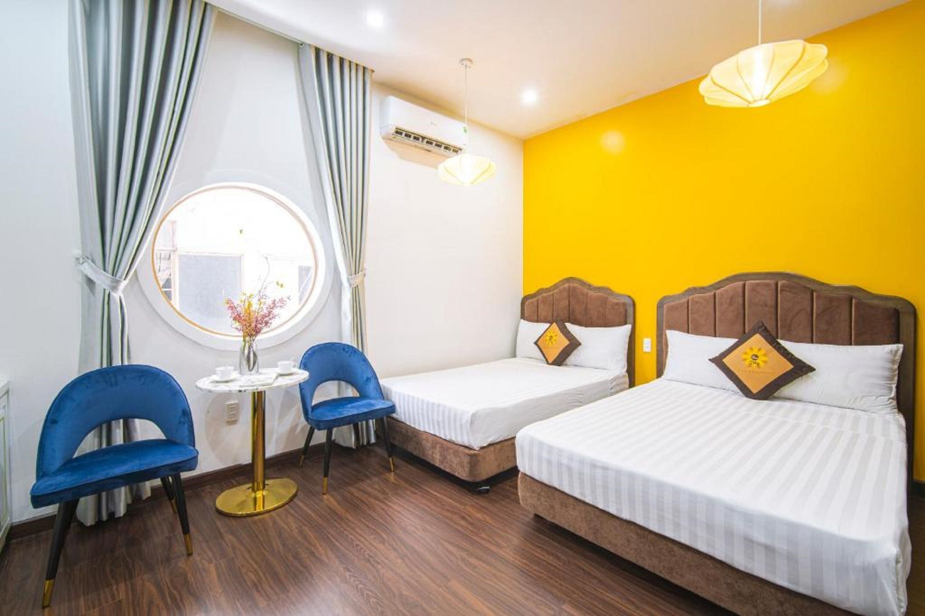 A hotel room with two beds, a round table with chairs, and a window with curtains.