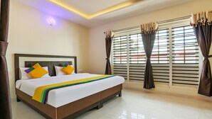 A hotel room with a large bed, a headboard, a window with blinds, and curtains. - Itsy Hotels Kottaram Residency, 10 Mins To Botanical Garden (Ootacamund)