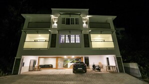 A two-story building with a garage entrance, a parked scooter, and a staircase leading to the upper floor. - Itsy Hotels Kottaram Residency, 10 Mins To Botanical Garden (Ootacamund)