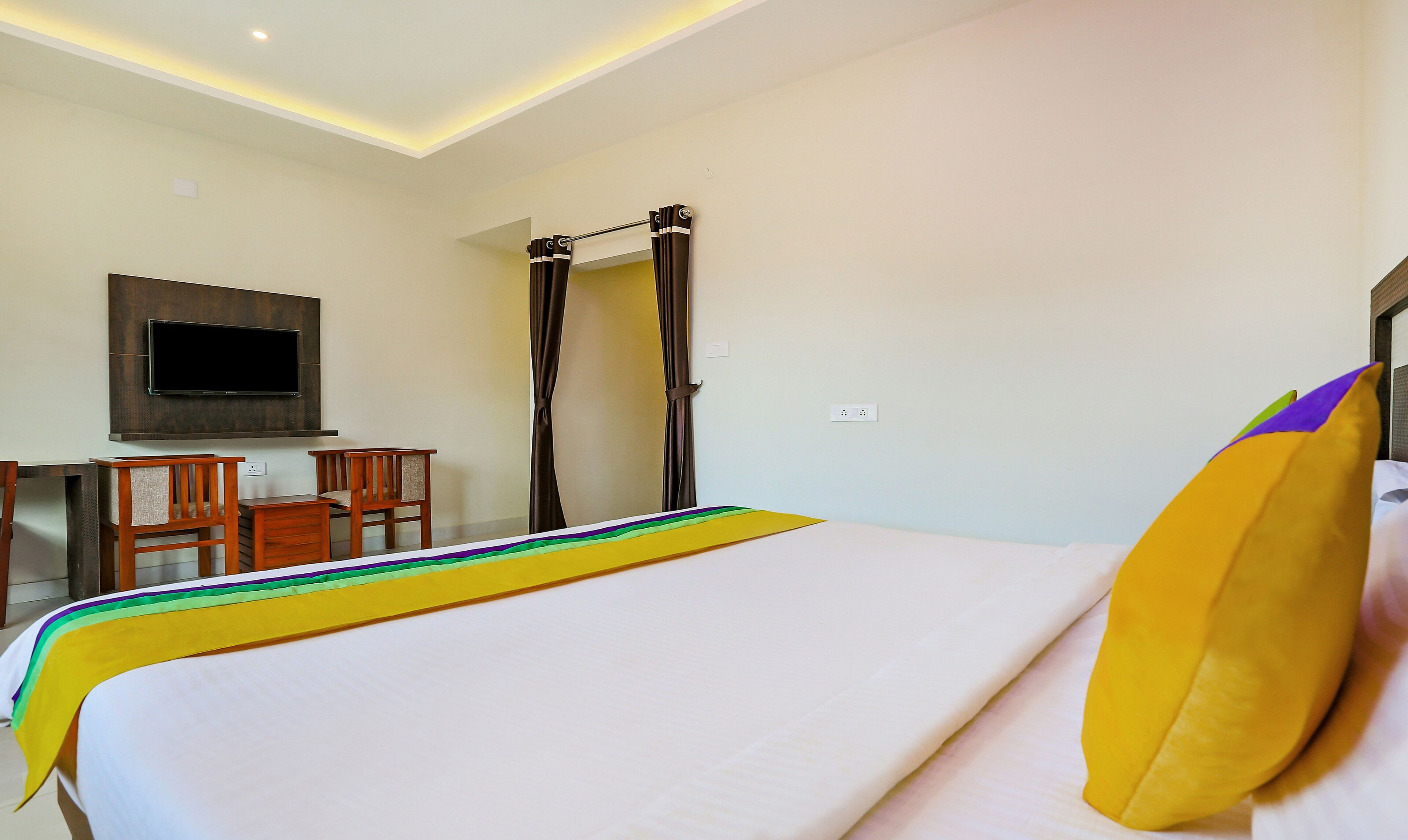 A hotel room with a bed, a desk, a chair, a television, and a curtain.