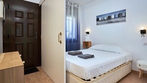Ein Schlafzimmer mit einem Bett, einem Nachttisch, einer Wandlampe und einem Gemälde.