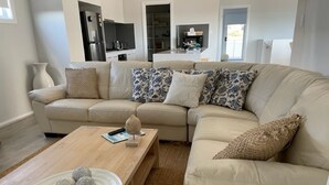 A modern living room with a beige sofa, a wooden coffee table, and decorative items.