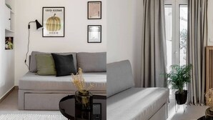 A modern living room with a grey sofa, a black floor lamp, and framed artwork on the wall. - Dreamy 1BR Apartment in Kolonaki (Athens)