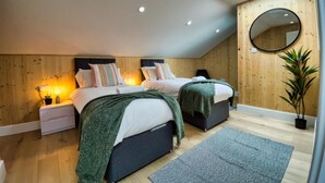 A bedroom with two beds, a skylight, a round mirror, and a potted plant. - Green Mews 1 By My Getaways (Hove)