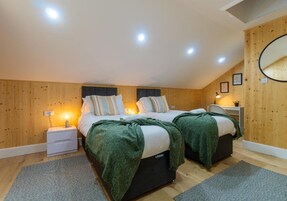 Un dormitorio acogedor con dos camas, paredes de madera y una lámpara en el techo.