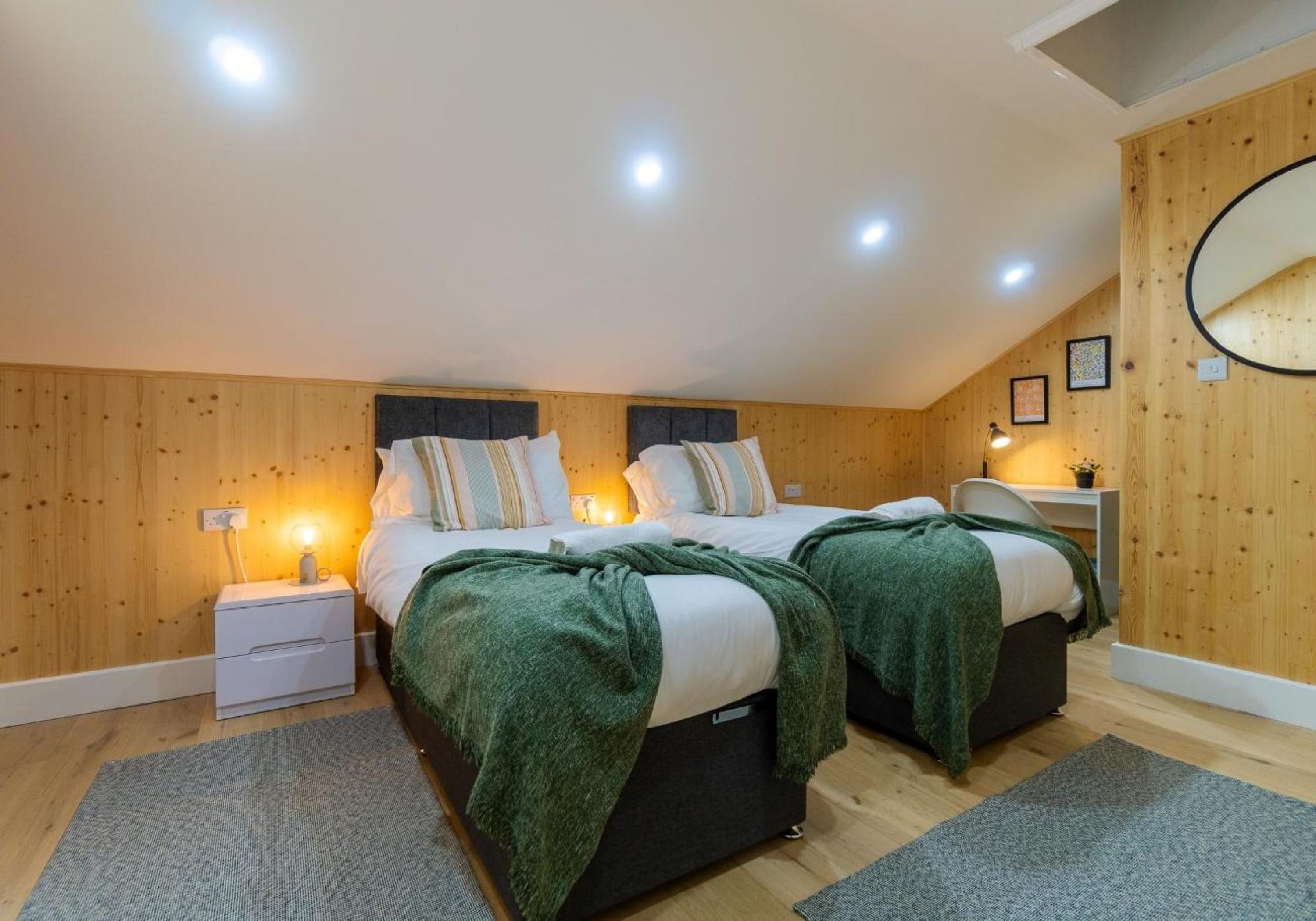 A cozy bedroom with two beds, wooden walls, and a ceiling light.