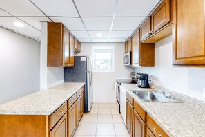 A compact kitchen with wooden cabinets, a refrigerator, a microwave, and a coffee maker.