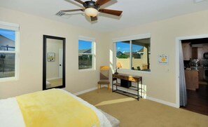 A bedroom with a bed, desk, chair, and a ceiling fan.