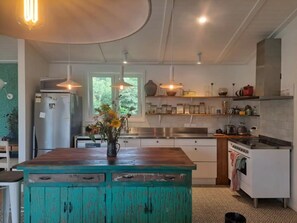 A kitchen with a central island, a refrigerator, a stove, and various kitchen appliances.