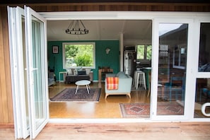 A modern interior with a sofa, a dining table, and a kitchen area visible through an open sliding door.