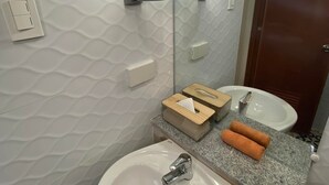 Een badkamer met een wit wastafel, een spiegel, een handdoekdispenser en een zeepbakje.