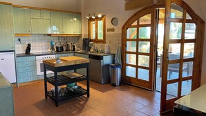 Une cuisine équipée d’un évier, d’une cuisinière et de placards. On y trouve une poubelle et une fenêtre donnant sur l’extérieur.