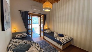 Une pièce confortable avec deux lits, un luminaire suspendu et une vue sur l’extérieur.