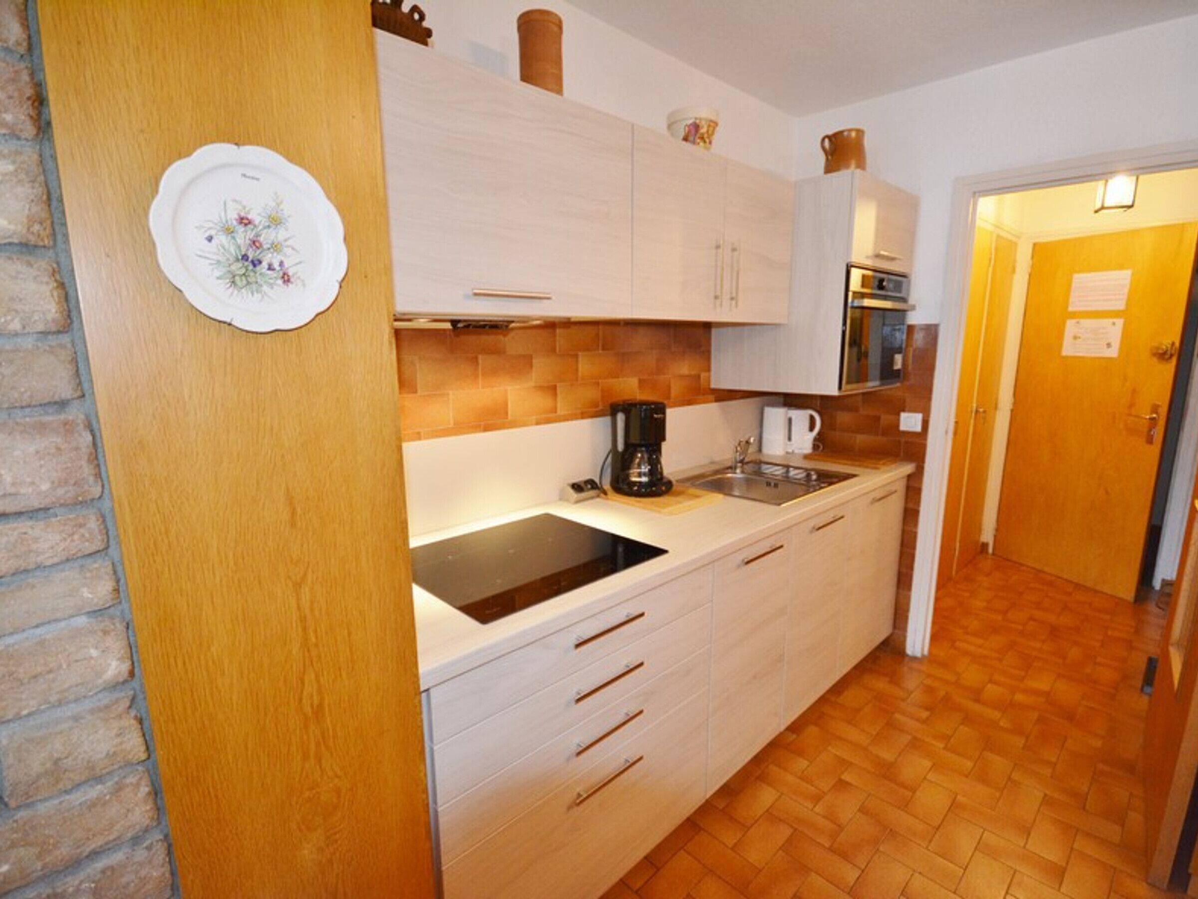 A kitchen with white cabinets, a black countertop, a coffee maker, and a sink.