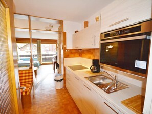A modern kitchen with a built-in oven, a coffee maker, and a sink.