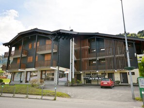 Un edificio de varios pisos con balcones, un coche rojo estacionado al frente y un letrero que dice "RESIDENCE D'AATRE".