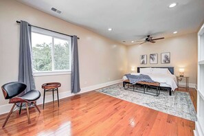 A bedroom with a bed, a chair, a small table, a ceiling fan, and a window with curtains. - Spacious and Fun 5BR w/ Pool Table and more! (Indianapolis)